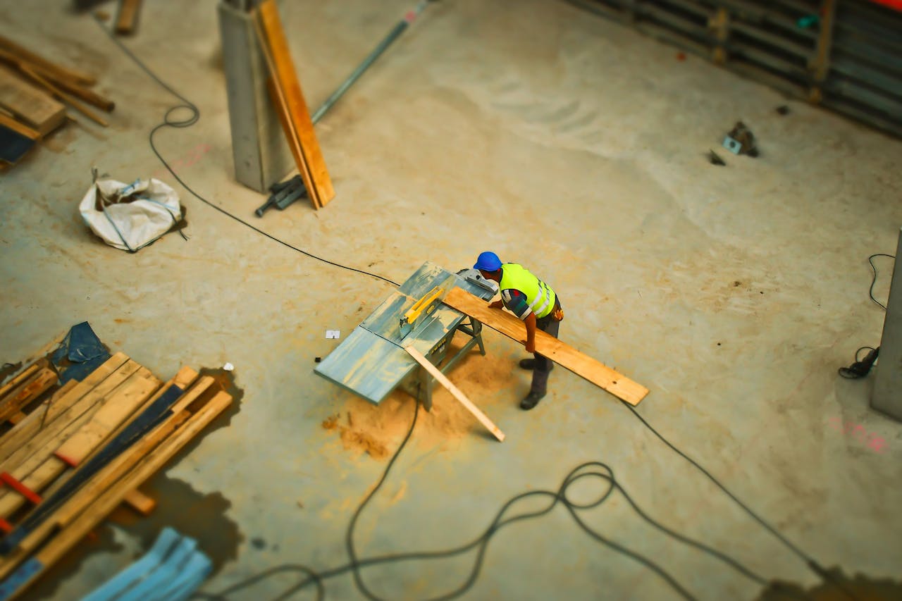 Services Overhead view of a construction worker using a saw to cut wood at a construction site.